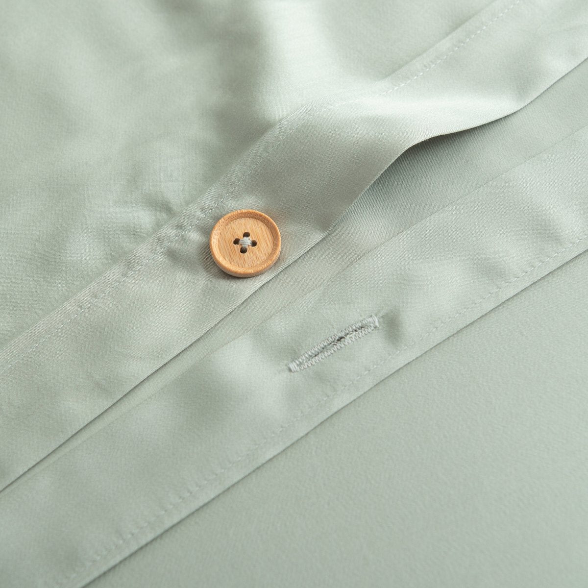 Button placket bedding in detail, soft morning light on linen texture