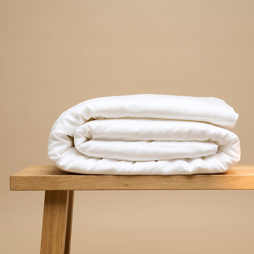 Down-filled duvet in a cream linen cover in soft morning light