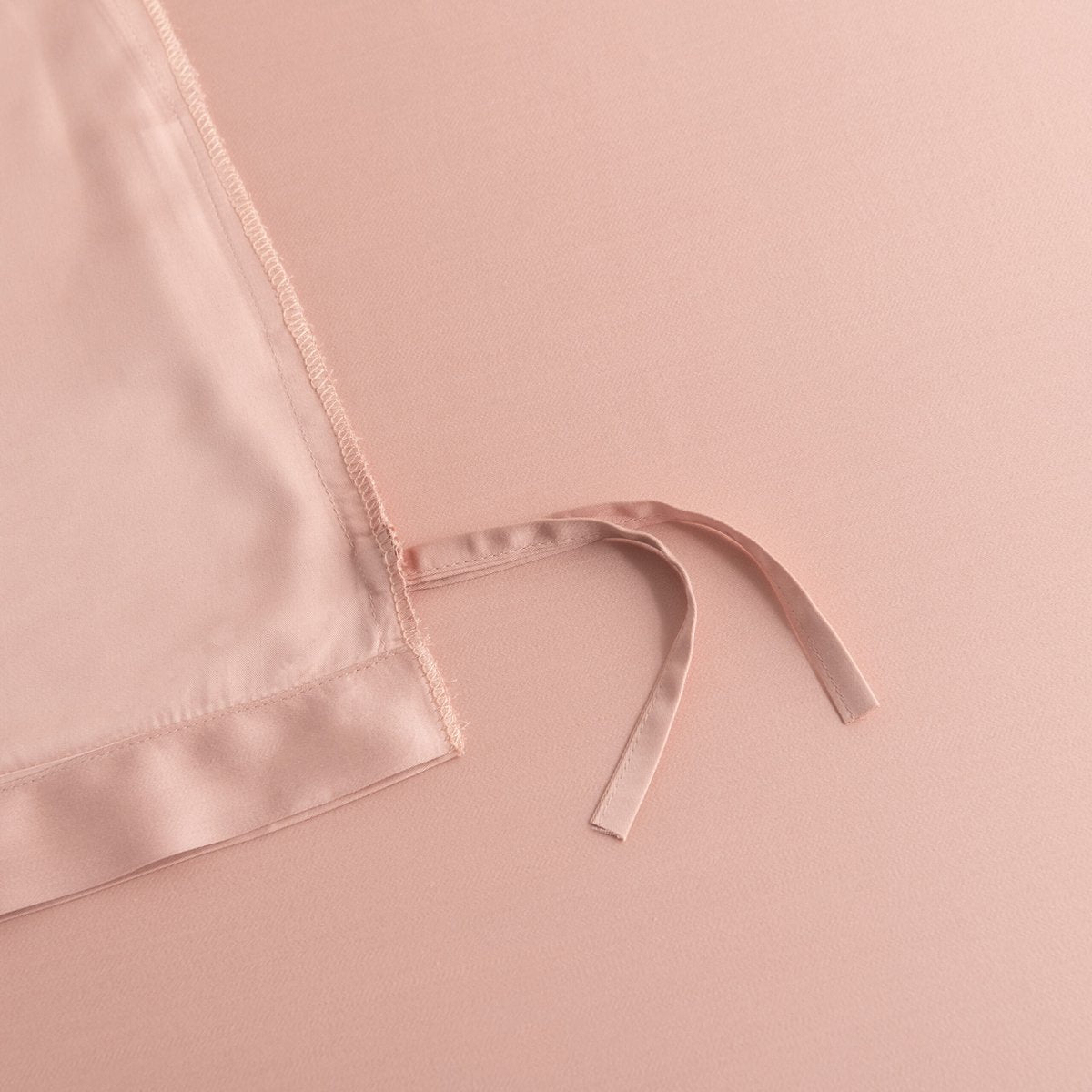 Close-up of the tuck-in strip ties on the corner of the Cuddle Pink bamboo duvet cover