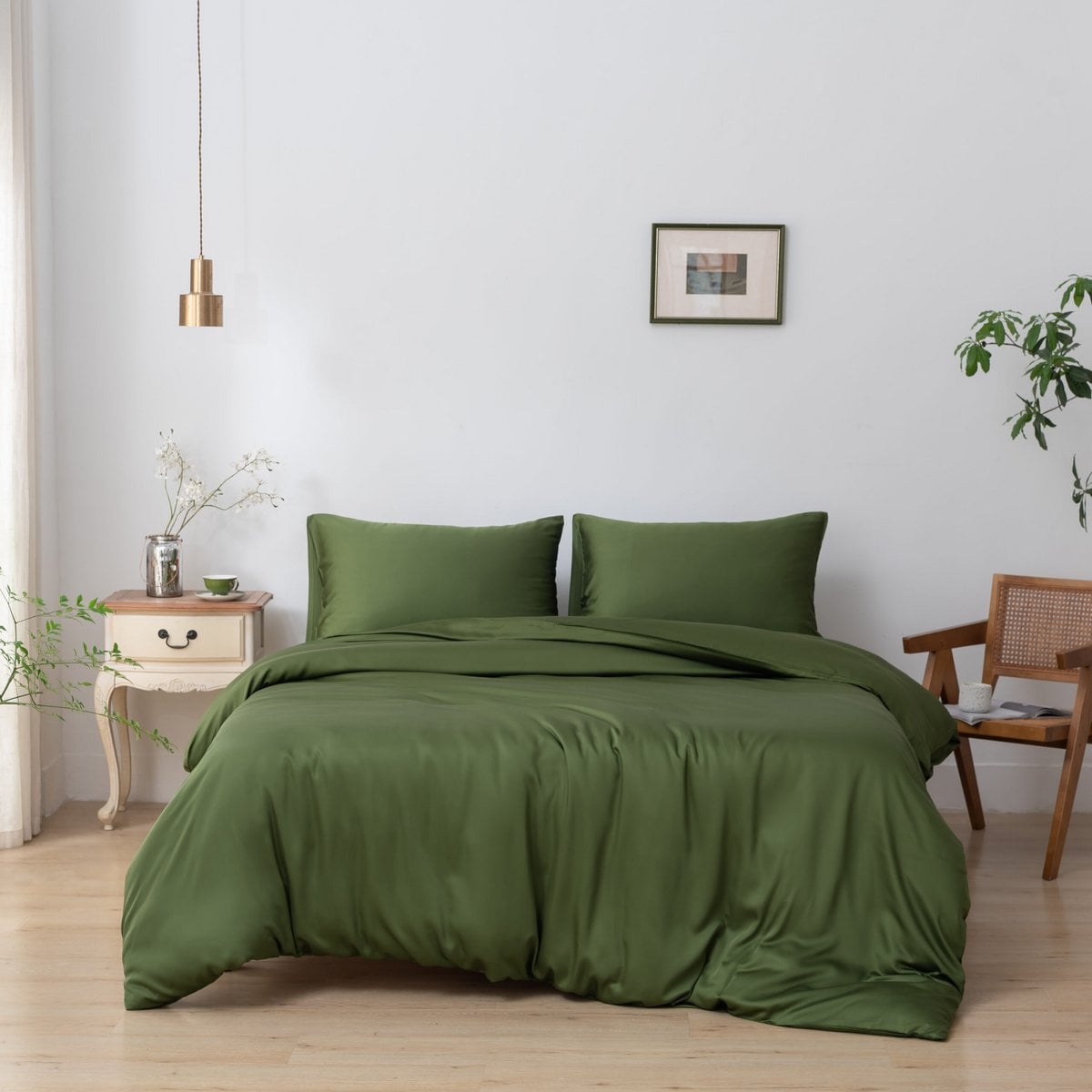 Bamboo duvet cover in Deep Moss on a bed beside a wooden nightstand with a cup and flowers