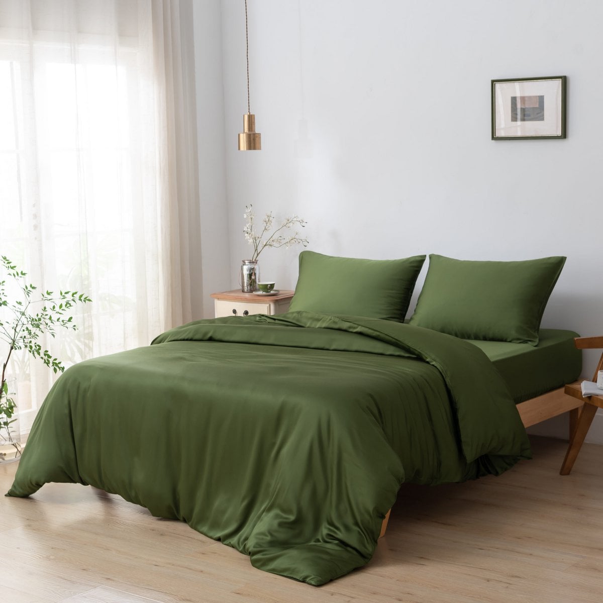 Bamboo duvet cover in Deep Moss on a bed beside a cane chair and wooden nightstand with a flower