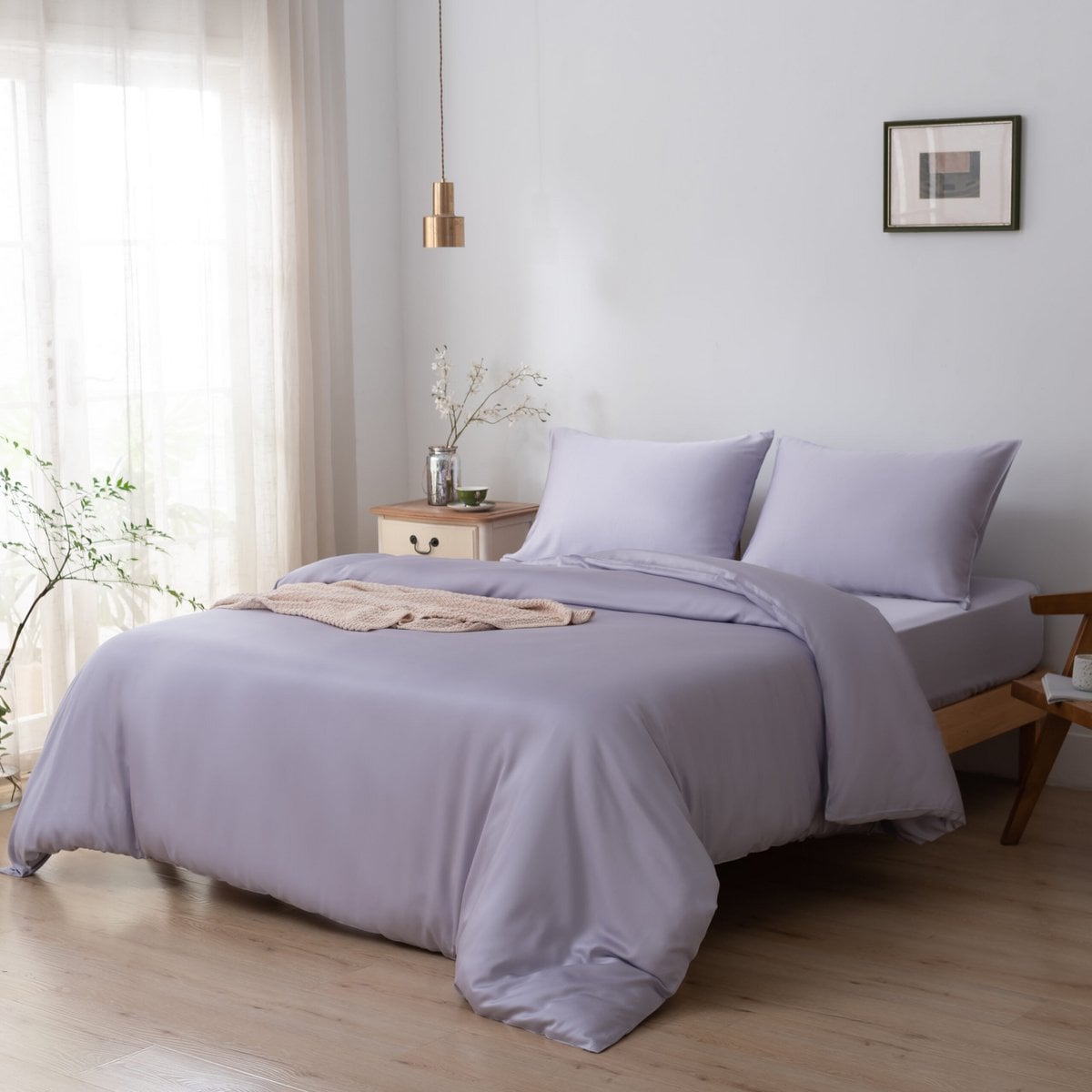 Bamboo duvet cover in Lavender Mist styled on a bed with a folded throw blanket, wooden nightstand, and hanging pendant light