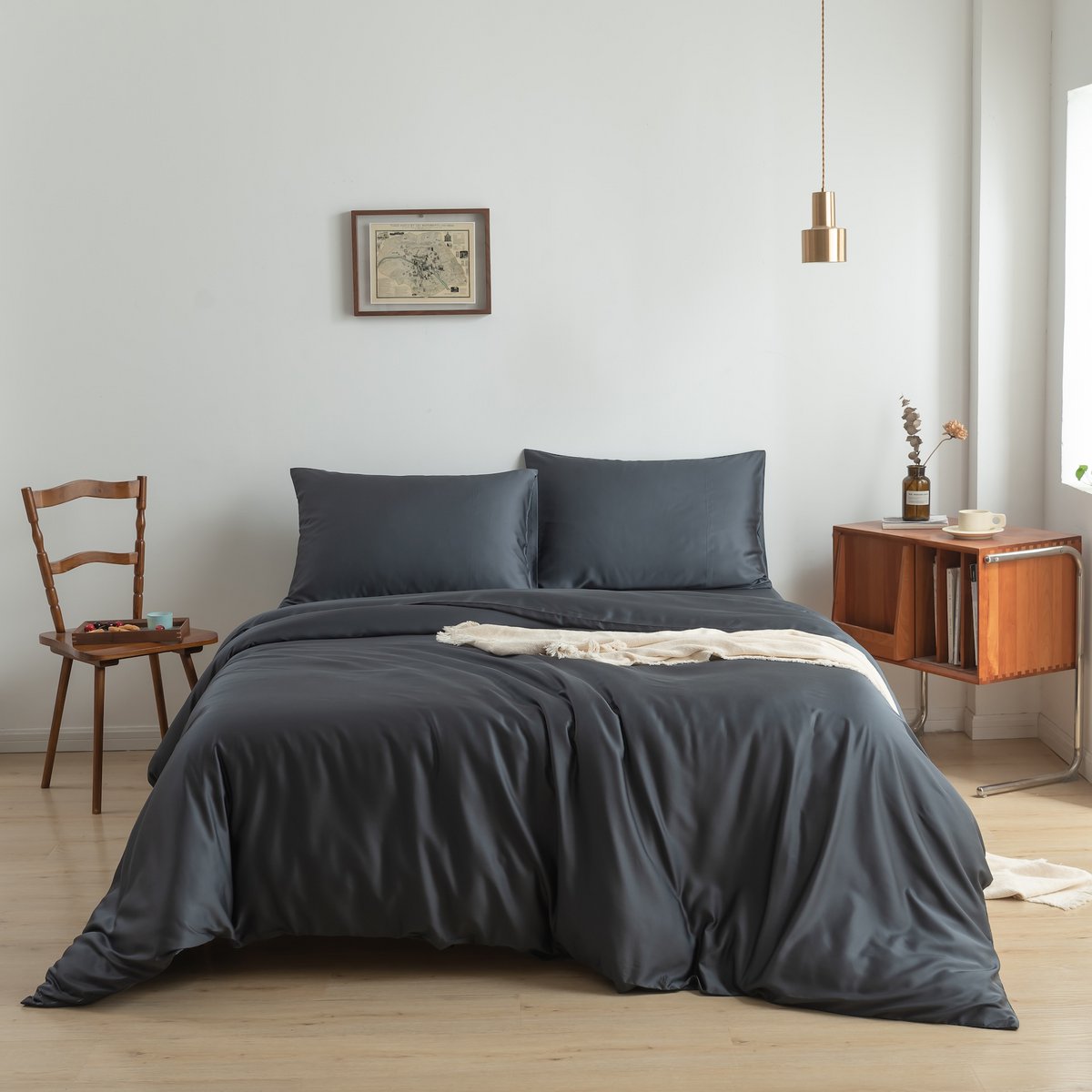 Bamboo duvet cover in Space Blue on a bed near a window with a potted plant and wooden nightstand