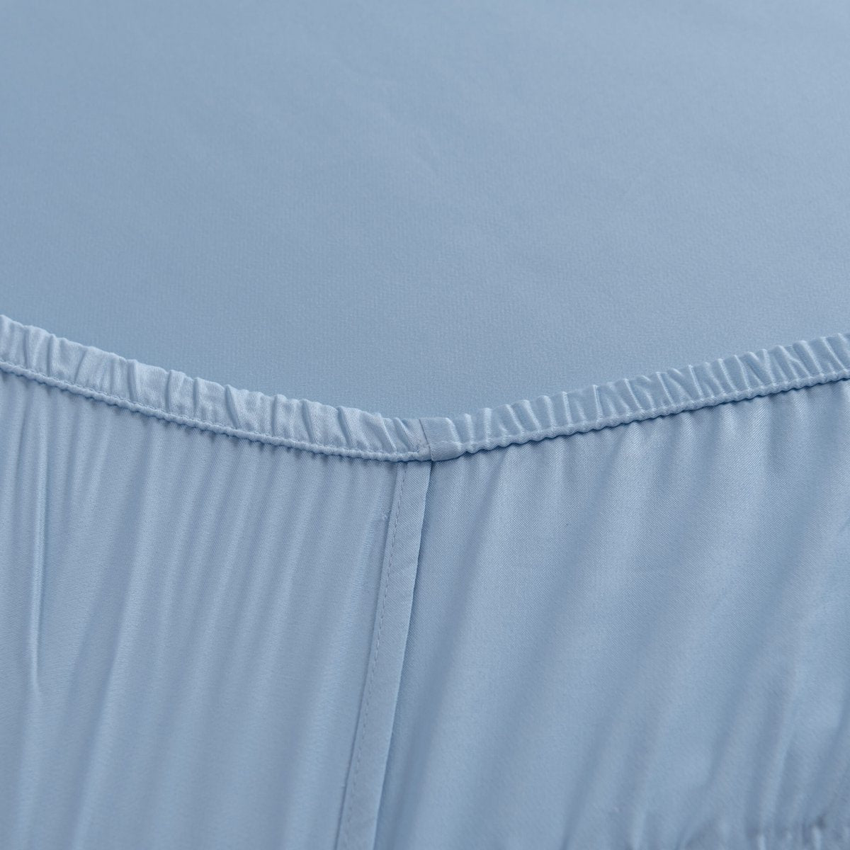 Close-up of the Sky Blue bamboo fitted sheet's elasticated corner and stitched seam.