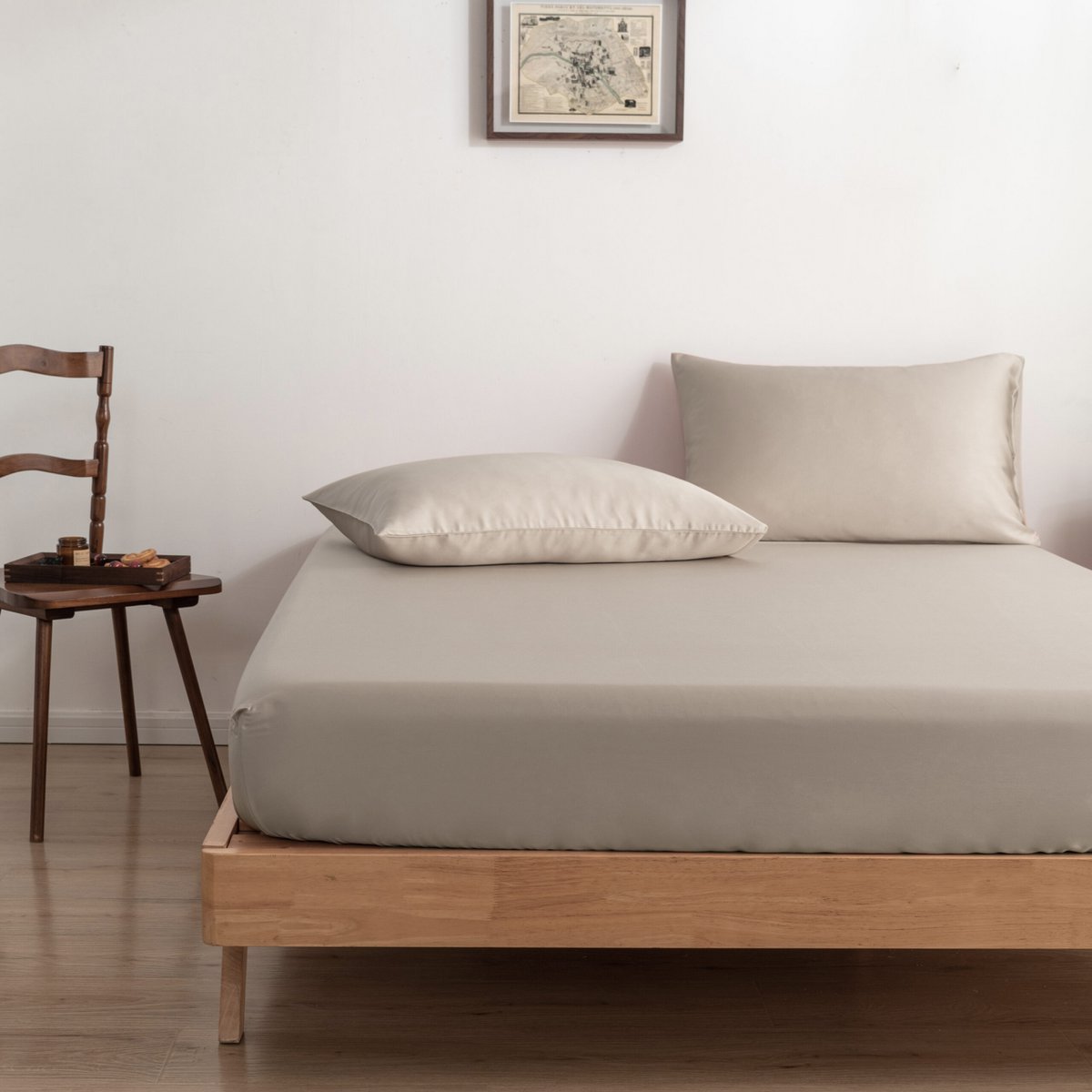 Soft Taupe bamboo fitted sheet on a bed beside a wooden chair with a breakfast tray.