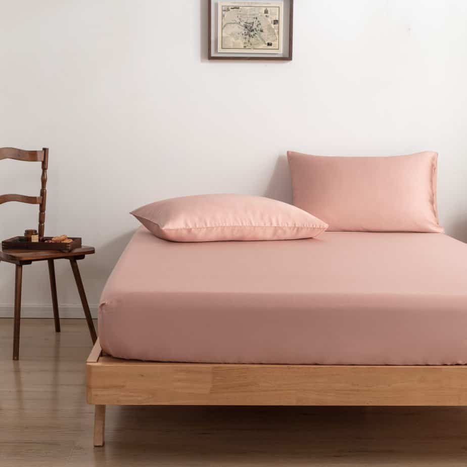 Cuddle Pink bamboo pillowcases on a wood-framed bed