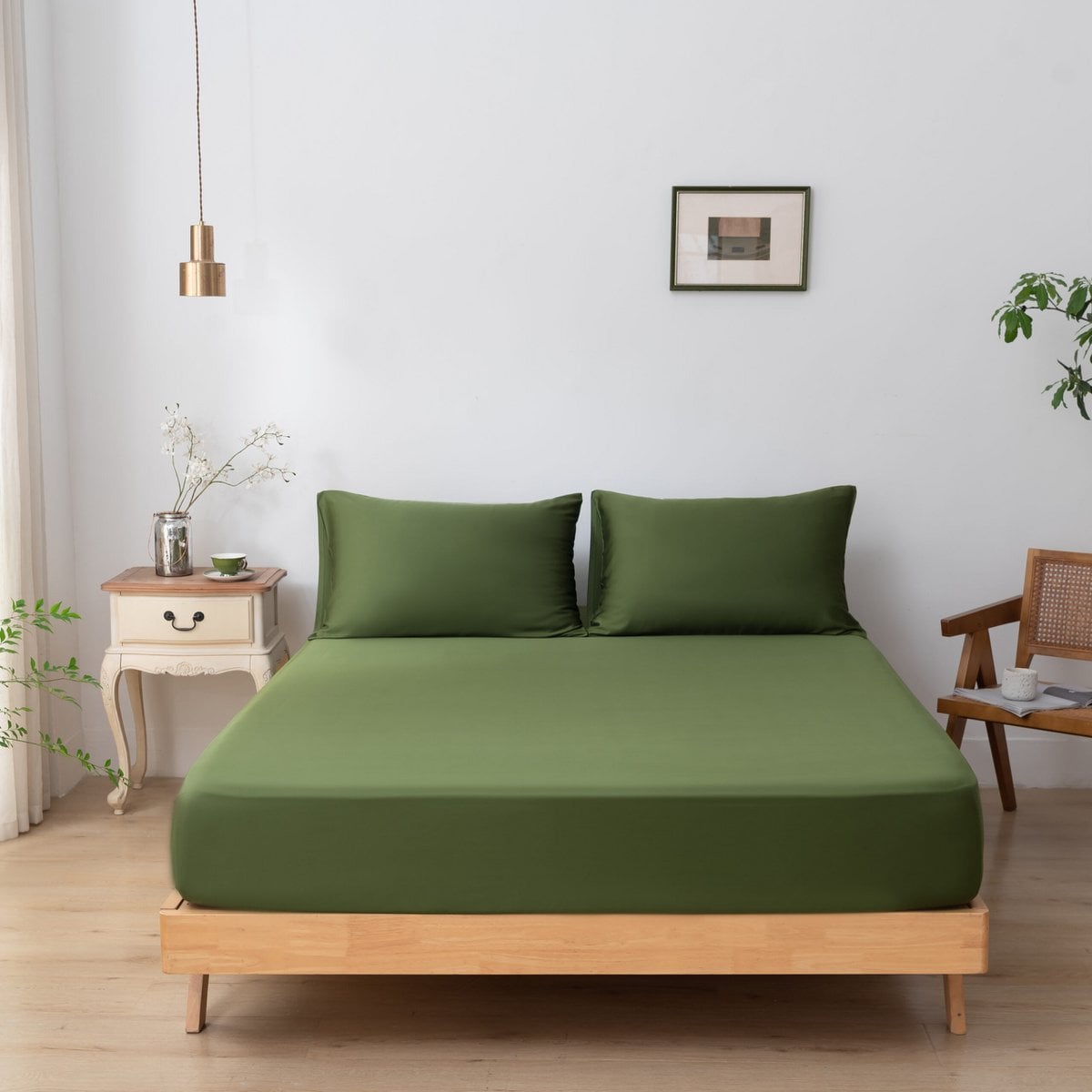 Deep Moss bamboo pillowcases styled on a bed by a window