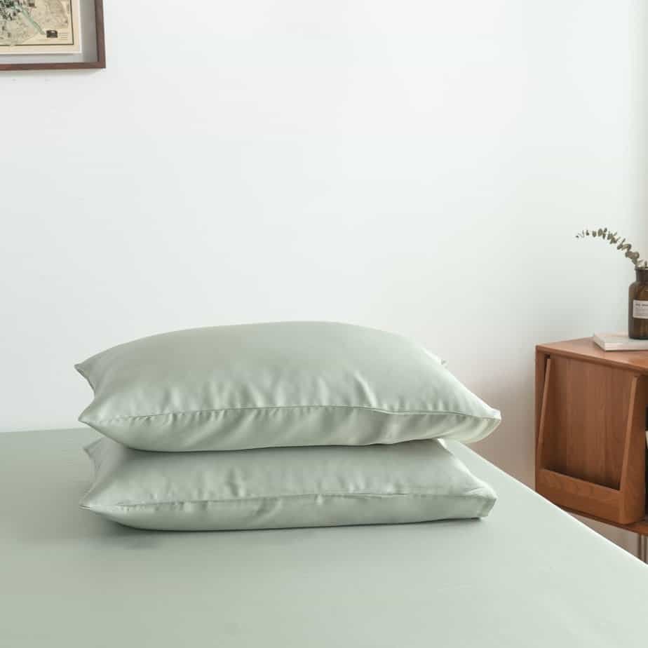 Sage Green bamboo pillowcases styled on a bench in a bedroom setting