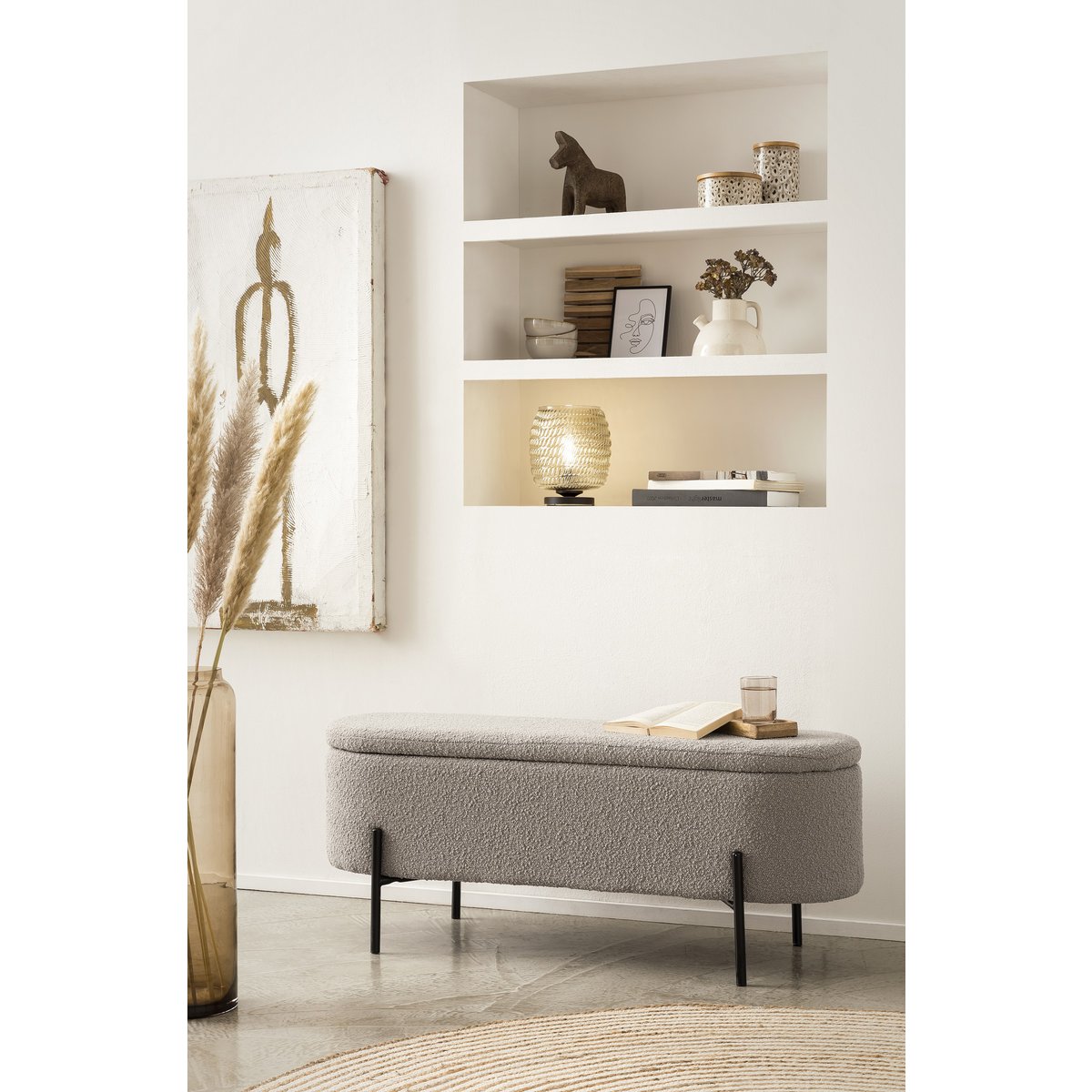 Banc de lit avec rangement en bouclé taupe avec couvercle fermé, mis en scène devant une niche à étagères