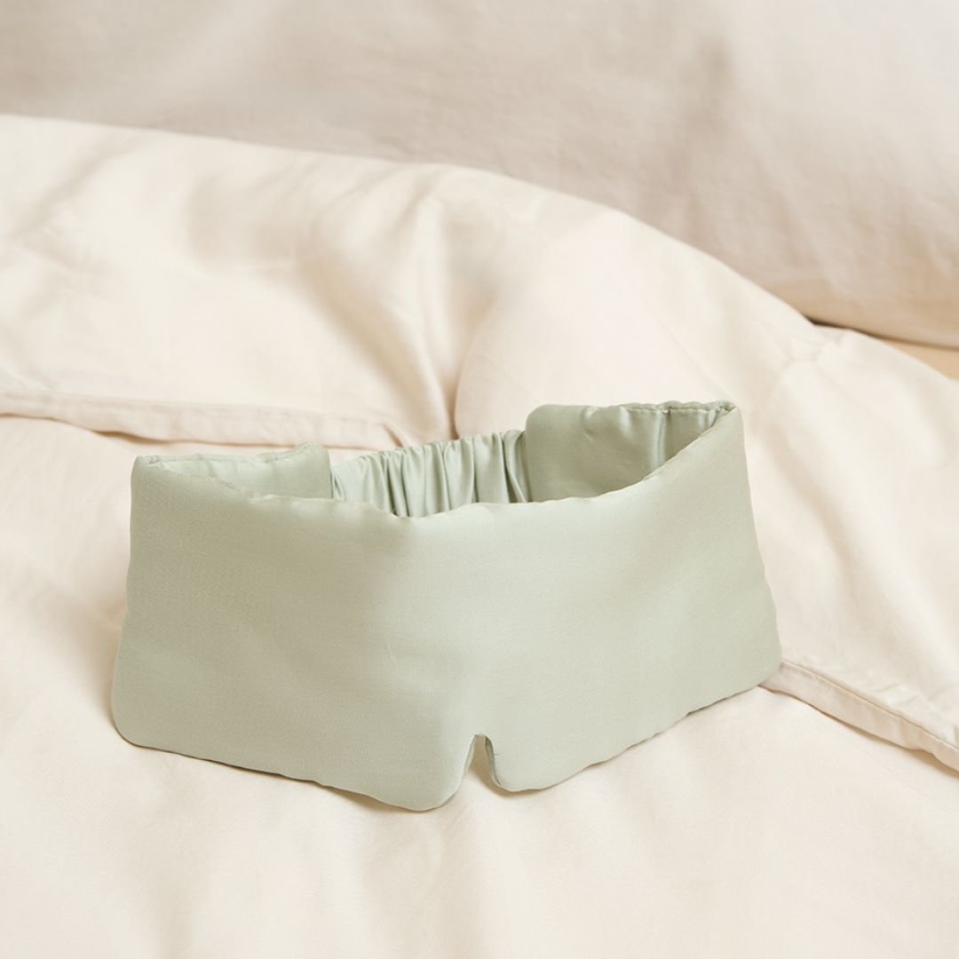 Gray Green sleeping mask lying on a bed cover
