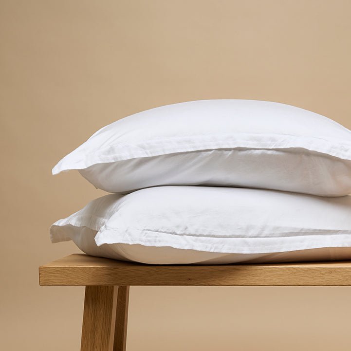 Tencel™ Twill Pillowcase in White stacked on a wooden bench