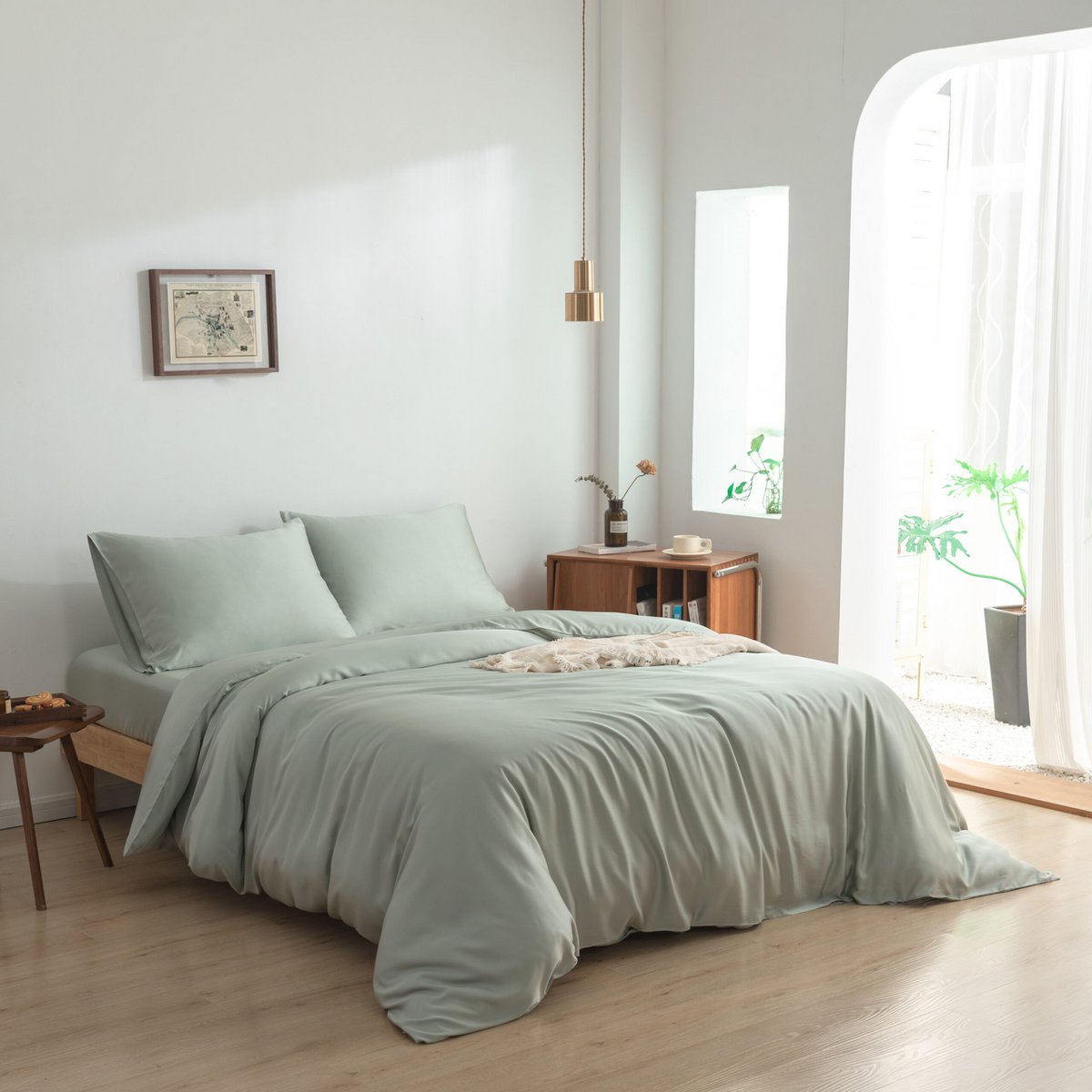 Sage Green bamboo bedding set styled on a bed by a bright window