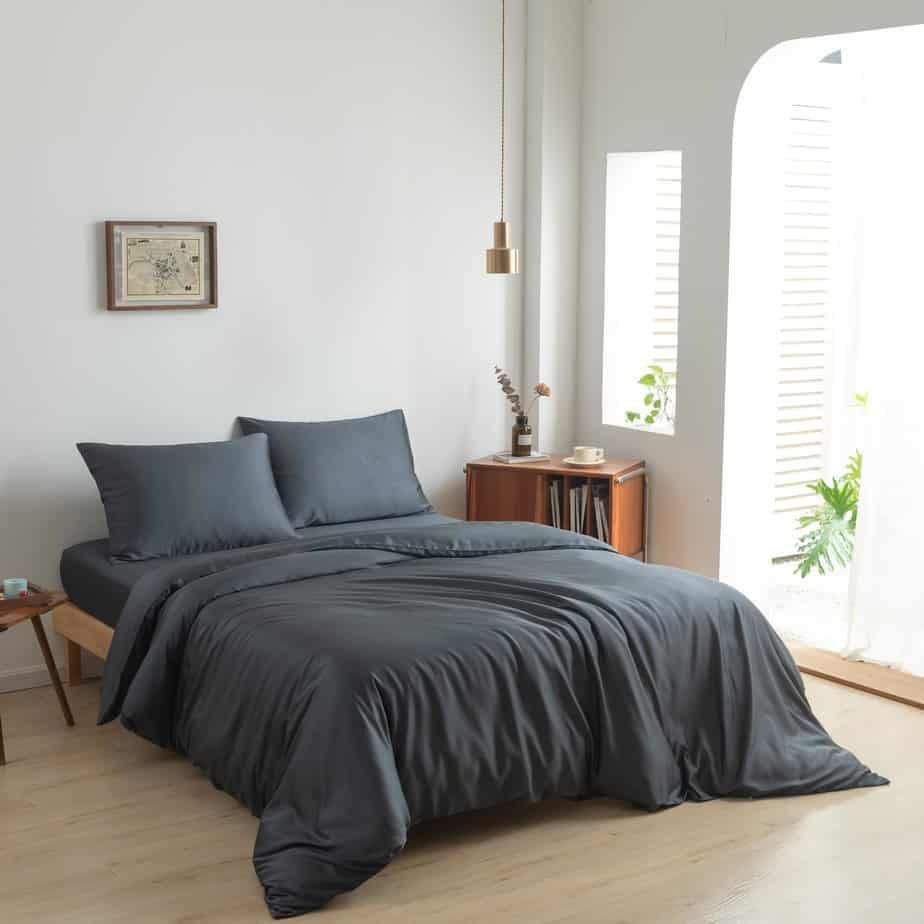 Space Blue bamboo bedding set styled on a bed by a window