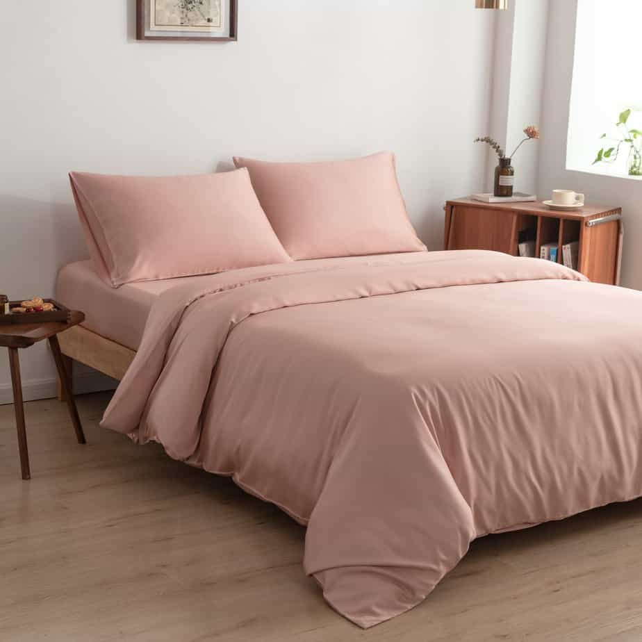 Bamboo duvet cover in Cuddle Pink styled on a bed in a bright bedroom with a framed print