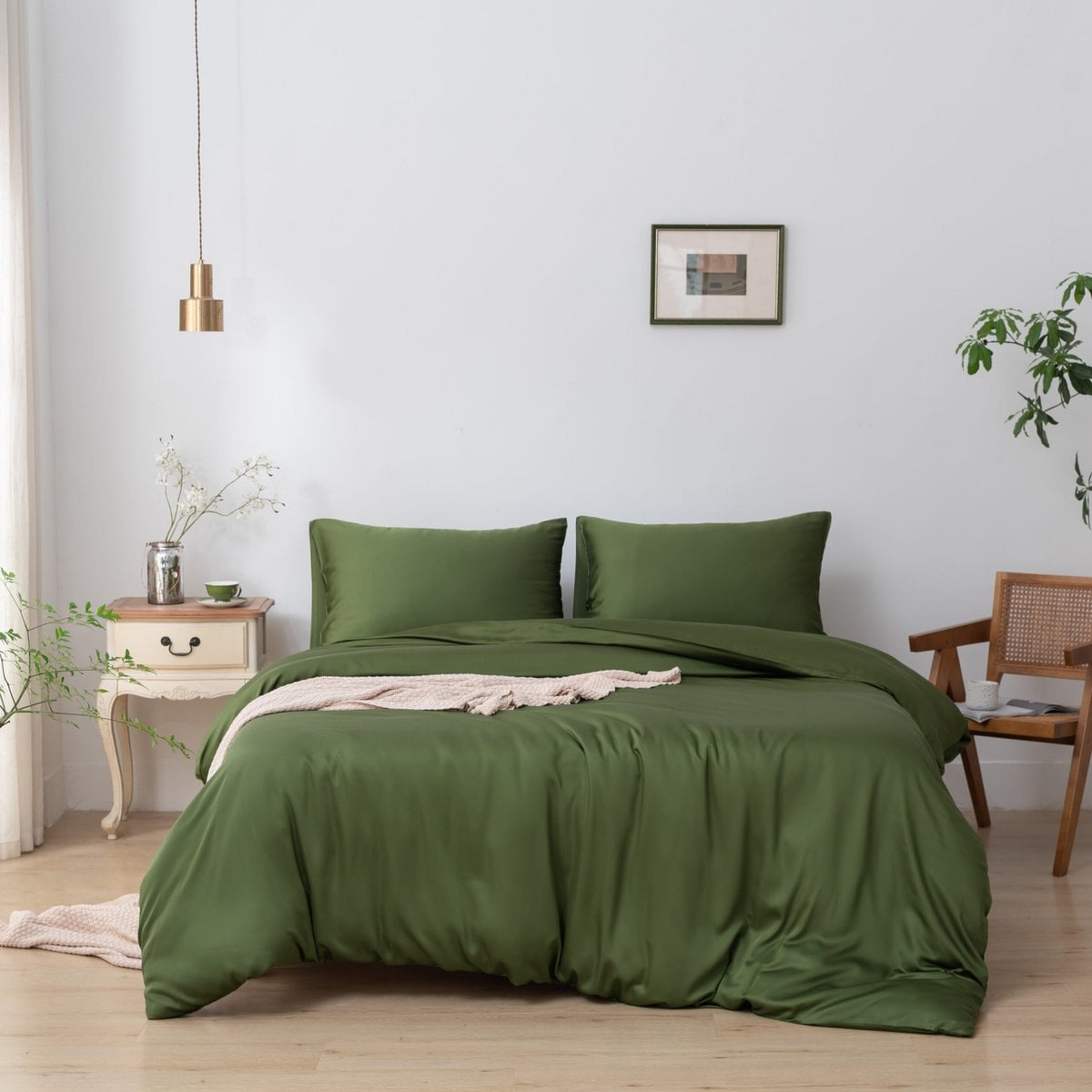 Bamboo duvet cover in Deep Moss on a bed beside a wooden chair and cream nightstand