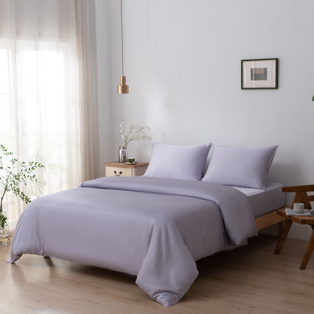 Bamboo duvet cover in Lavender Mist on a bed in a bright bedroom with a cream nightstand and potted plant