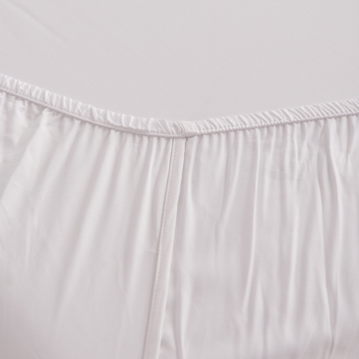 Close-up of the Coco White bamboo fitted sheet's corner seam and elastic stitching.