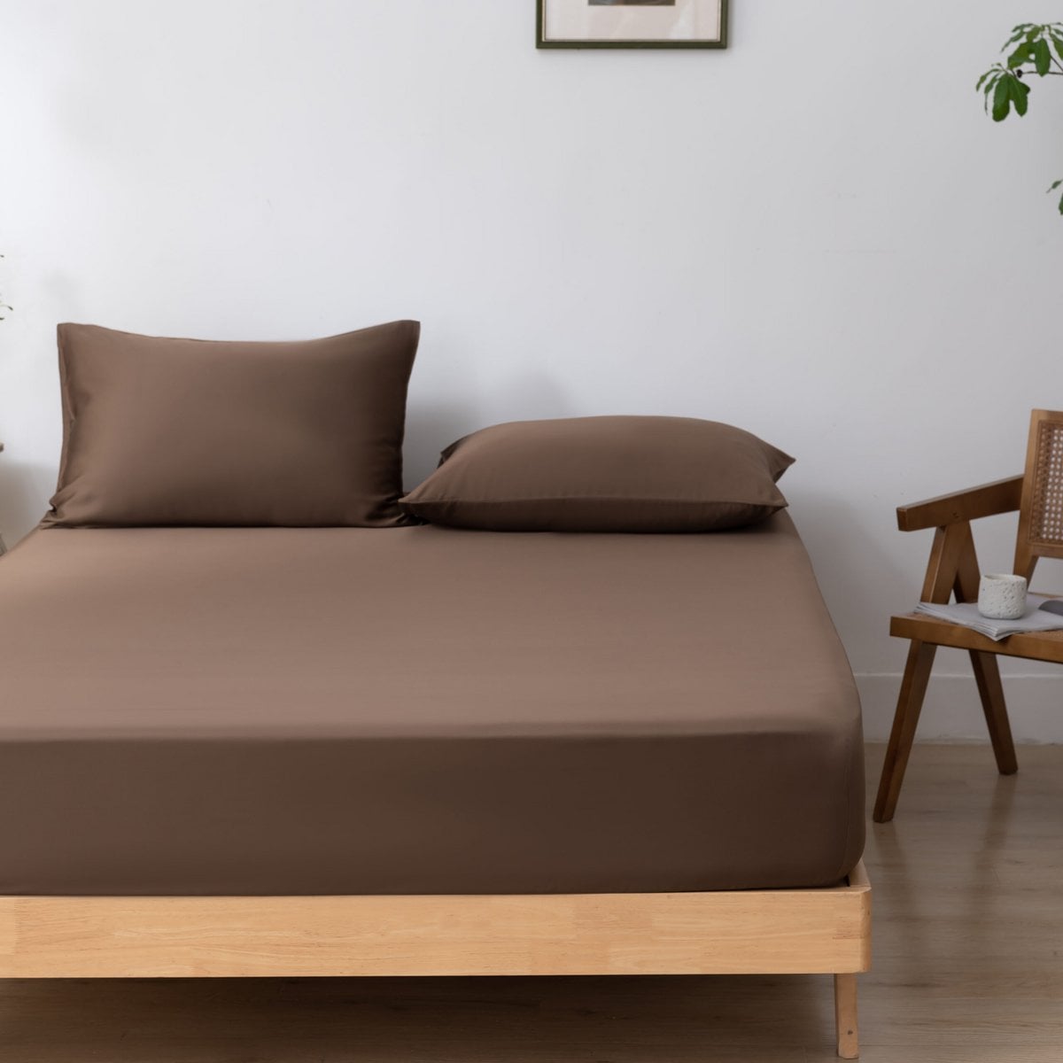 Coffee Brown bamboo fitted sheet on a bed beside a wooden chair with a cup and journal.
