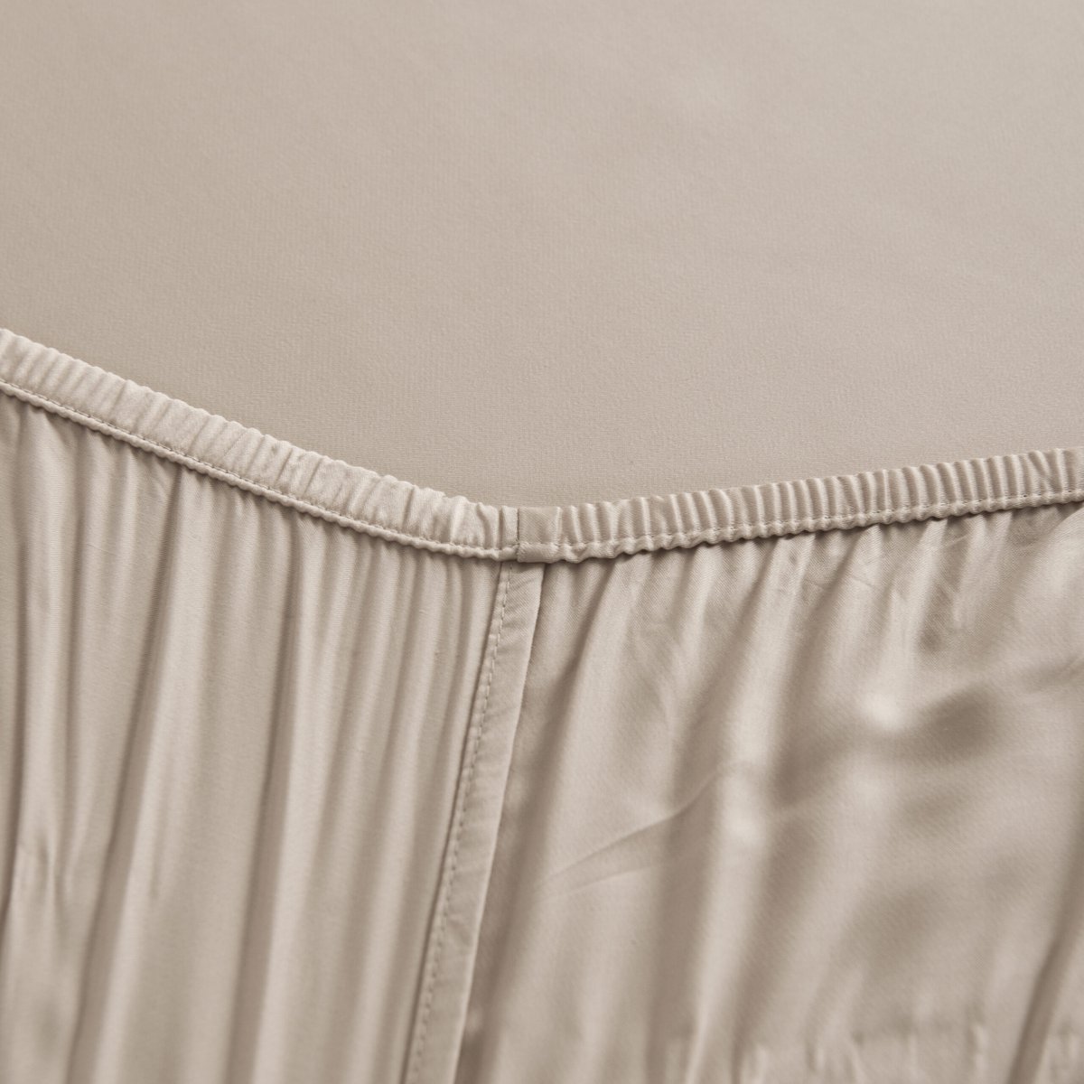 Close-up of the Soft Taupe bamboo fitted sheet's elasticated corner seam.