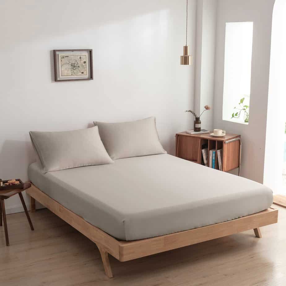Soft Taupe bamboo fitted sheet styled on a wood-frame bed in a bright bedroom.
