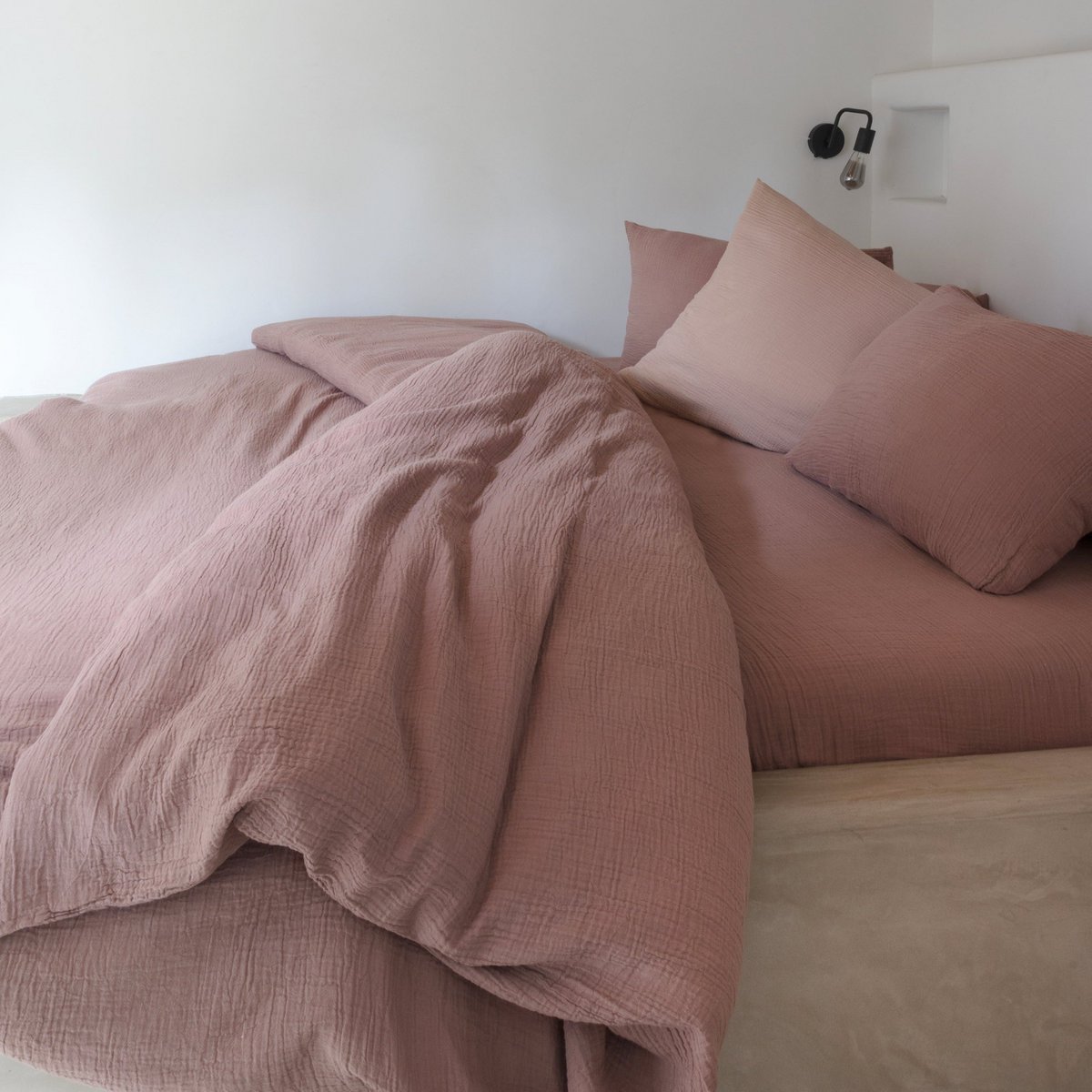 Dusty rose-toned cotton muslin duvet cover and pillowcases arranged on a bed