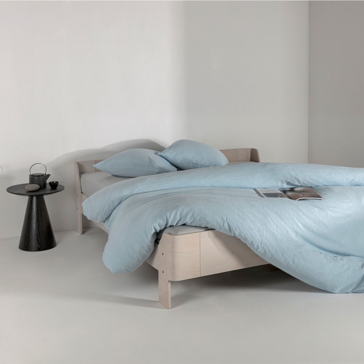 Ice blue cotton muslin duvet cover and pillowcases styled on a bed in a minimalist bedroom