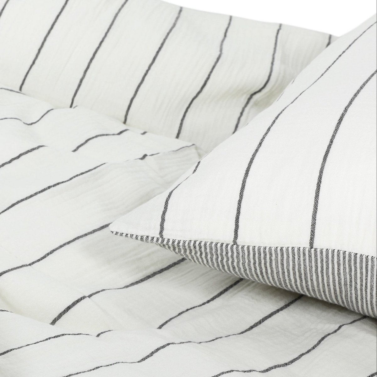Close-up showing both sides of the reversible cotton muslin fabric — fine pinstripe on one side, solid ticking stripe on the other