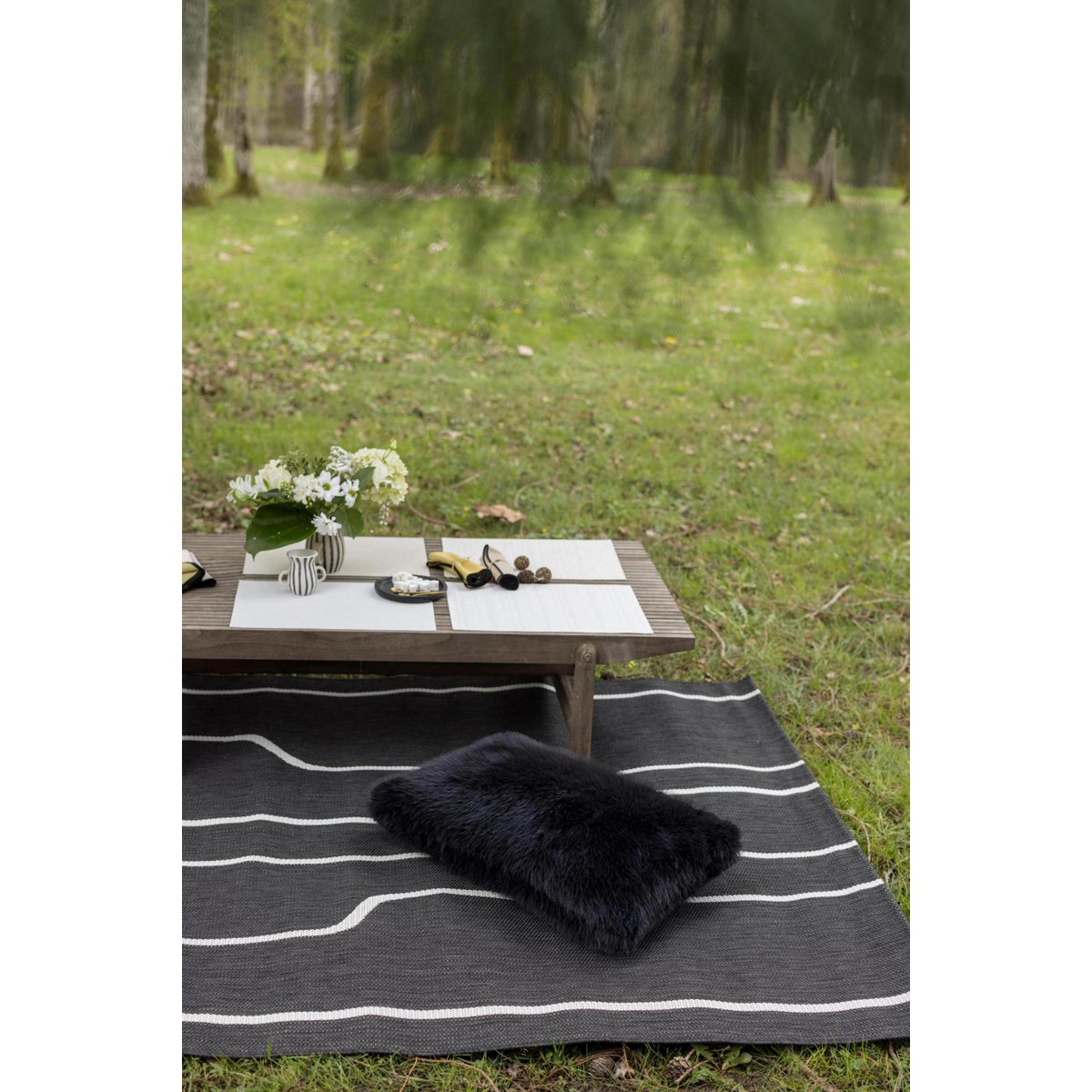 Ein Nolan-Kissen in tiefem Schwarz auf einem Teppich im Freien