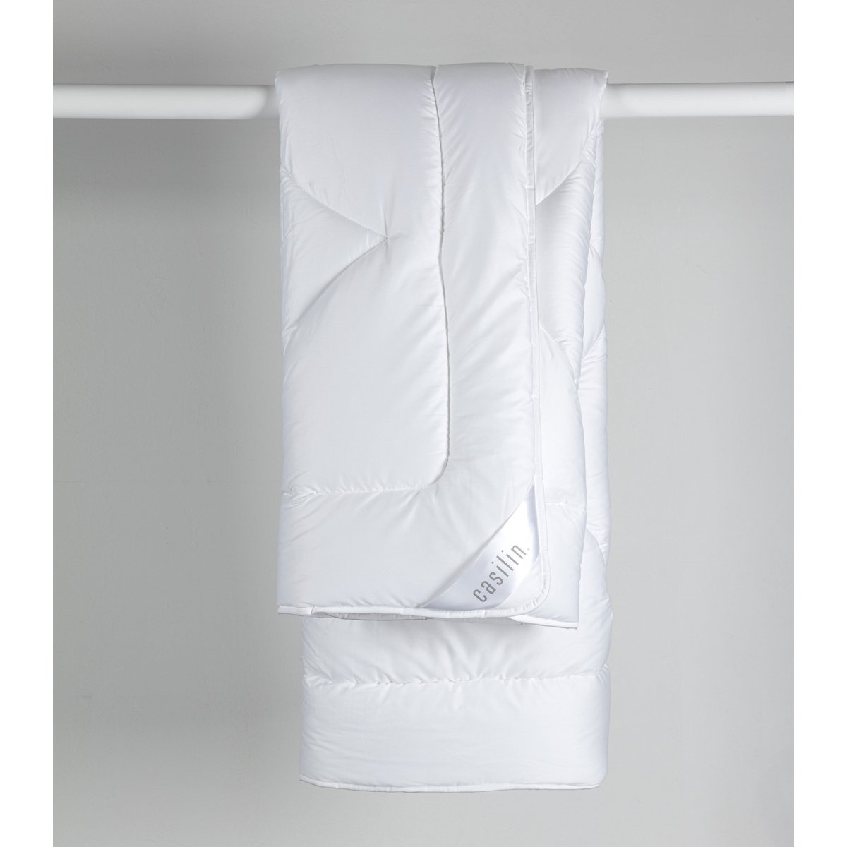 White Casilin Satin Duo duvet hanging folded, showing the sateen sheen and Casilin label