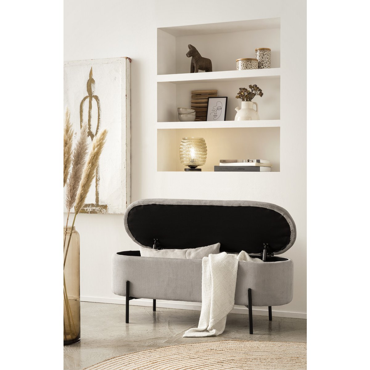 Banc de lit avec rangement en velours côtelé gris clair avec couvercle ouvert et un plaid posé sur le bord