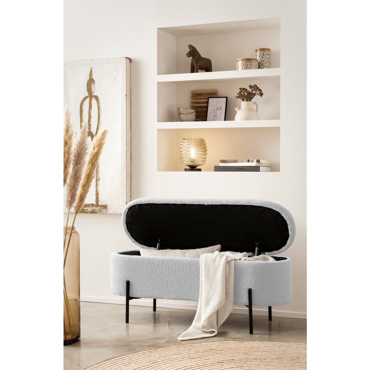 Banc de lit avec rangement en bouclé blanc avec couvercle ouvert et un plaid posé sur le bord