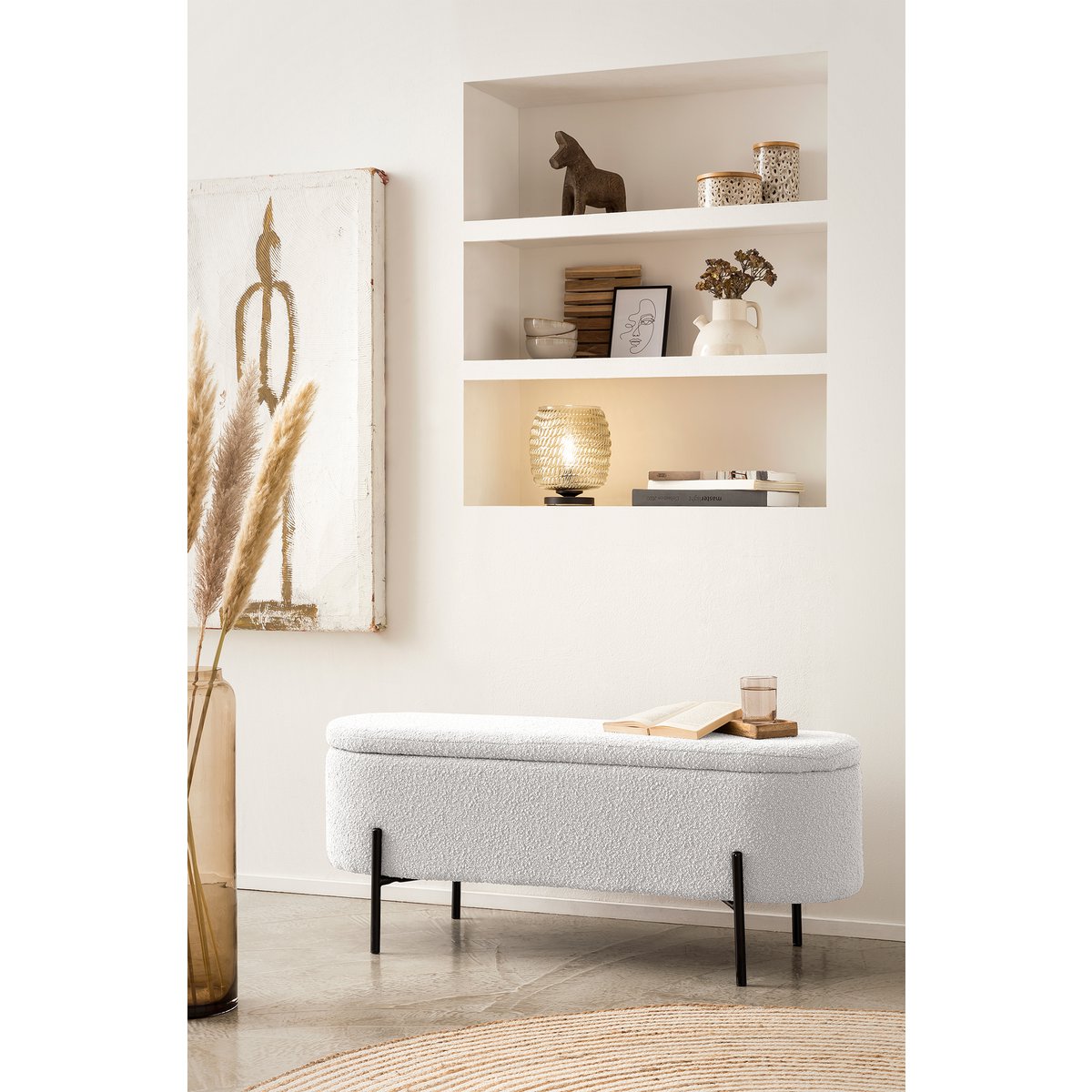 Banc de lit avec rangement en bouclé blanc avec couvercle fermé, mis en scène devant une niche à étagères