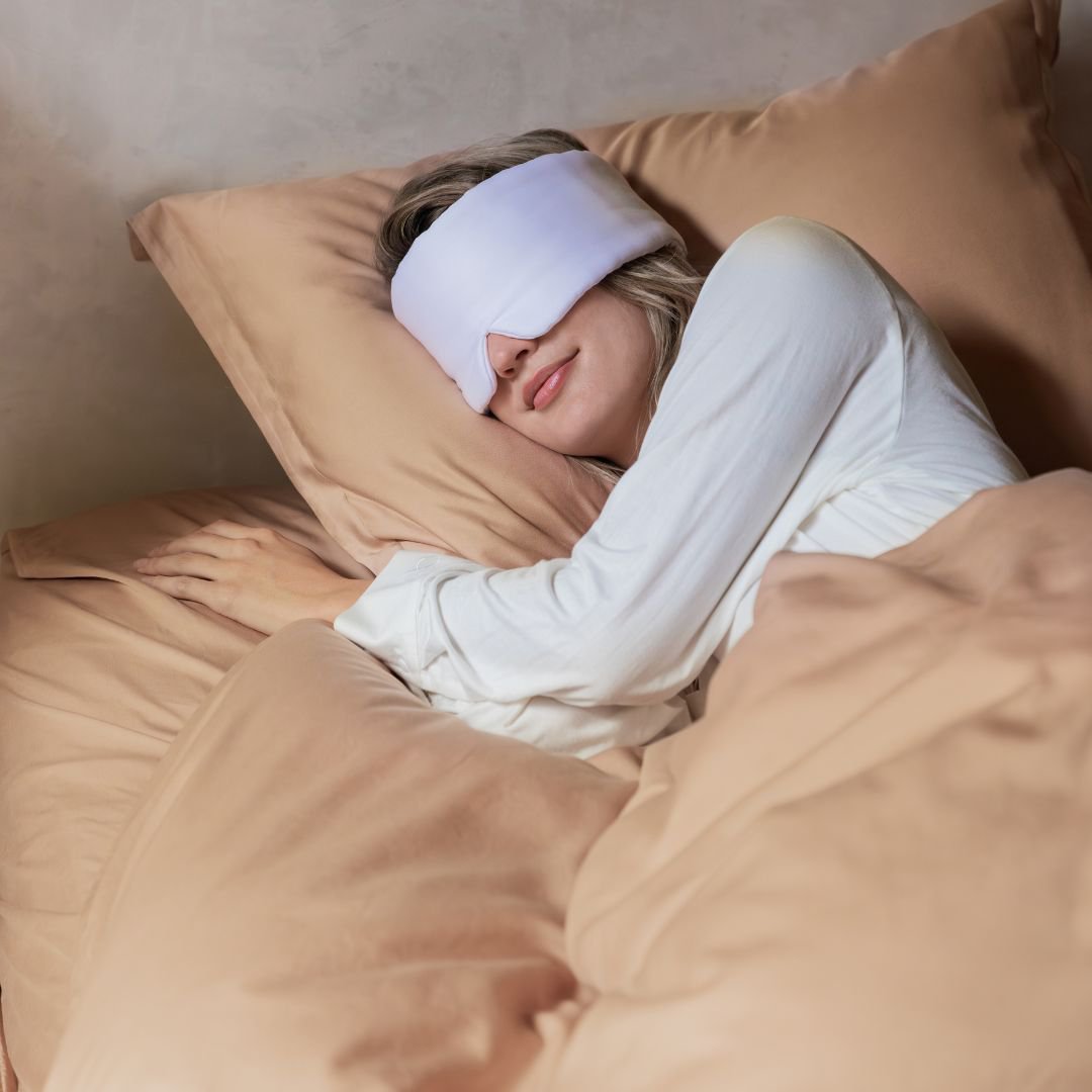 Woman lying in bed wearing the White sleeping mask