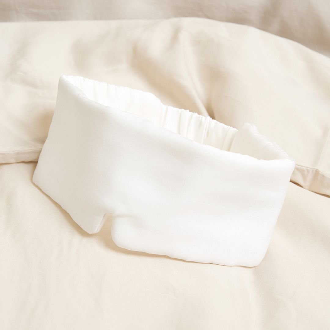 White sleeping mask lying on a bed cover