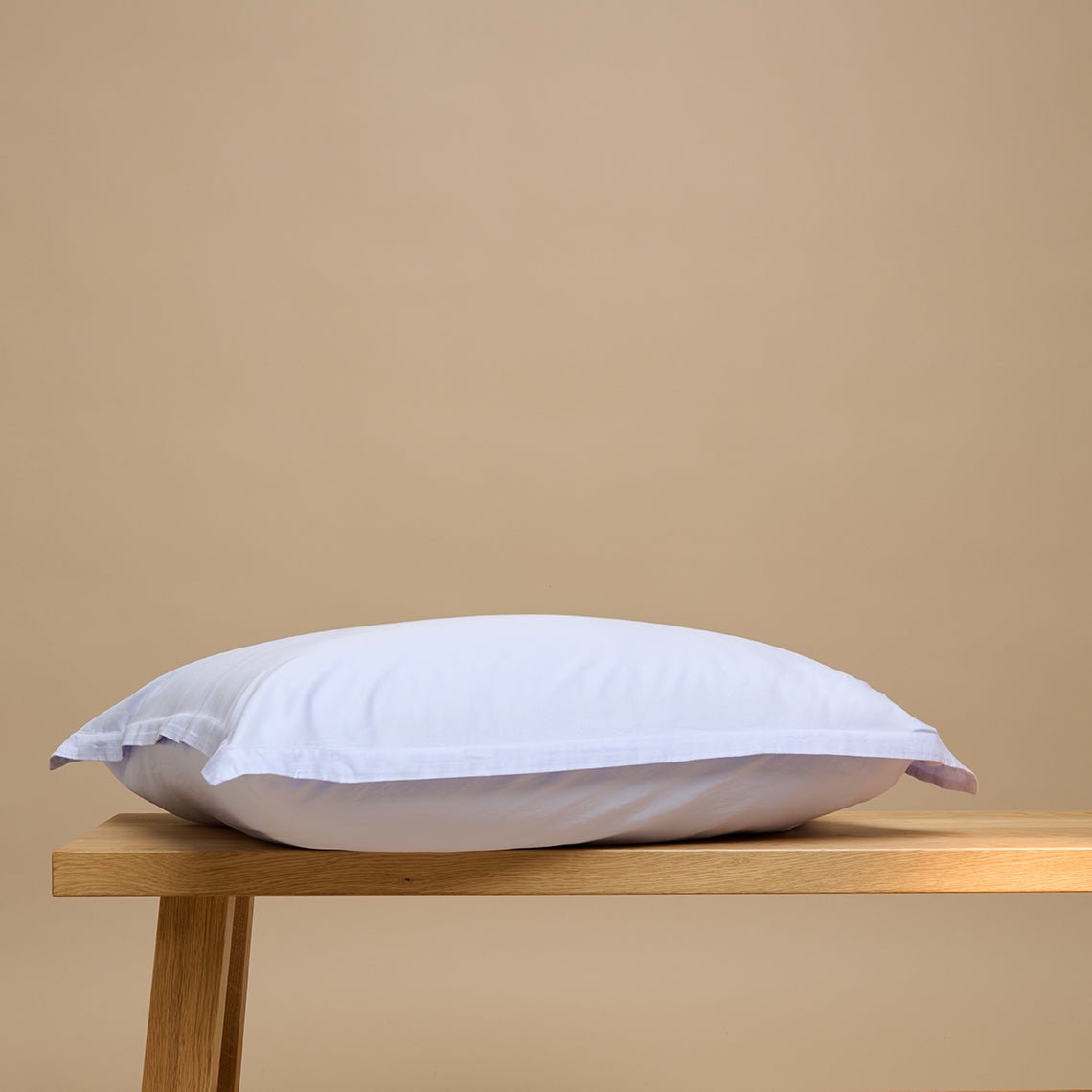 Tencel™ Twill Pillowcase in Lavender Blue shown from the side on a wooden bench